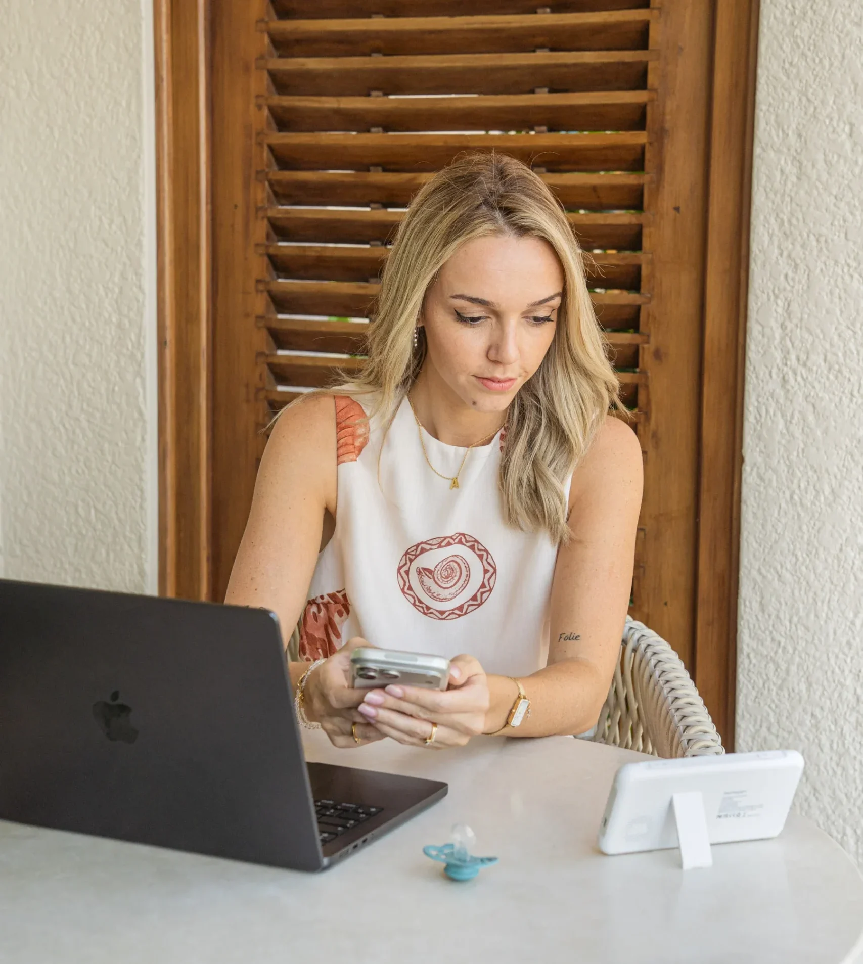 Femme assise à une table utilisant son smartphone et ordinateur